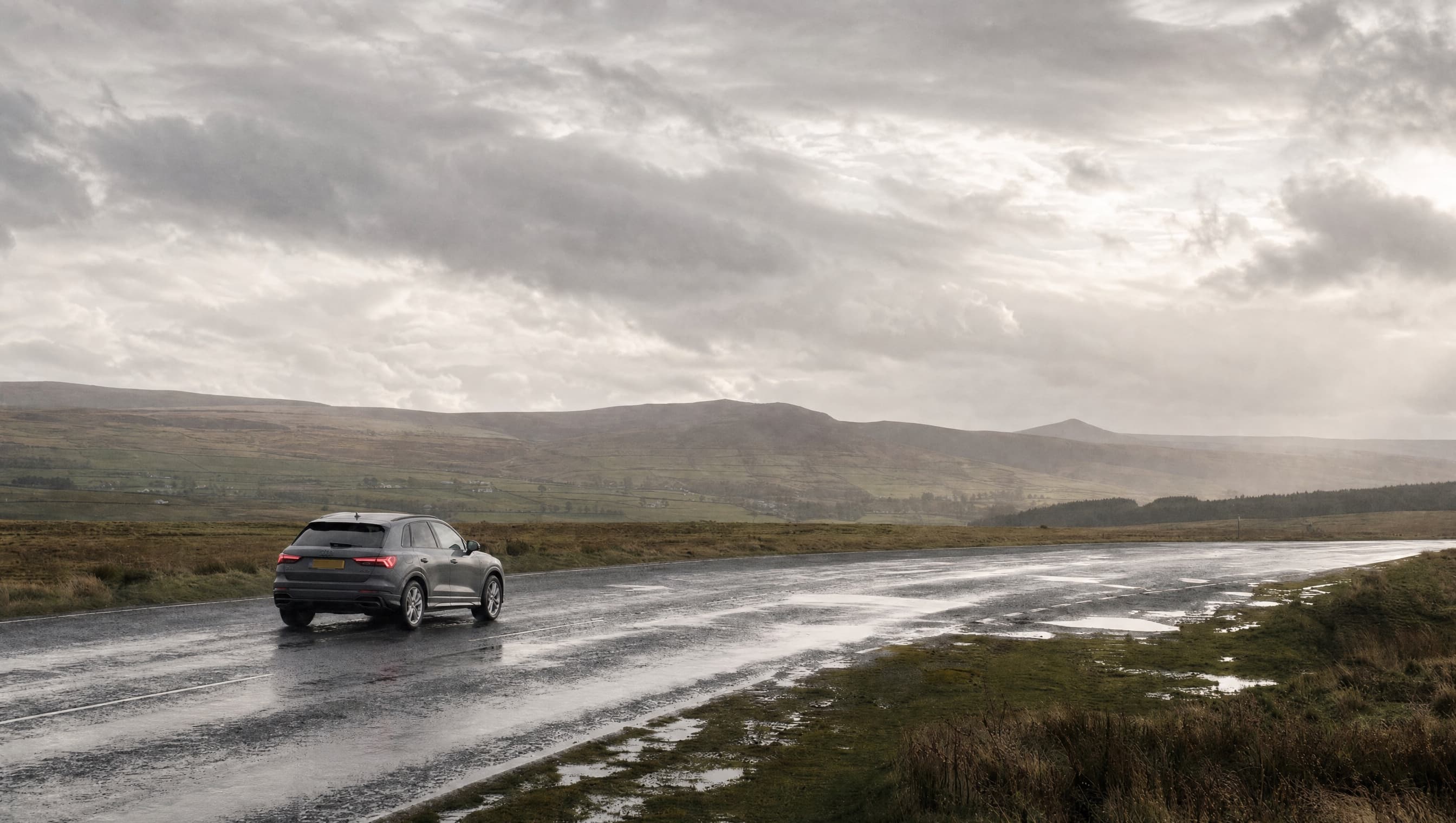 A car driving towards the mountains on an open road